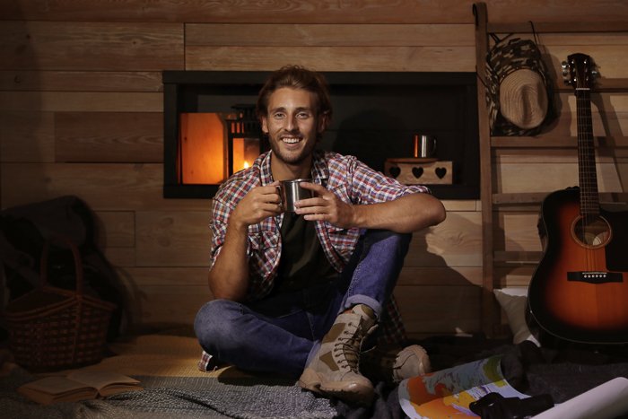 Handsome young traveler with mug indoors
