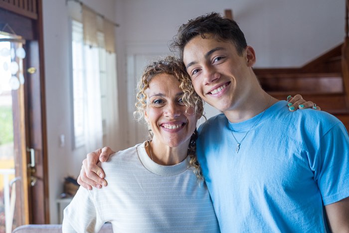 Portrait of grateful teenager man hug smiling middle-aged mother